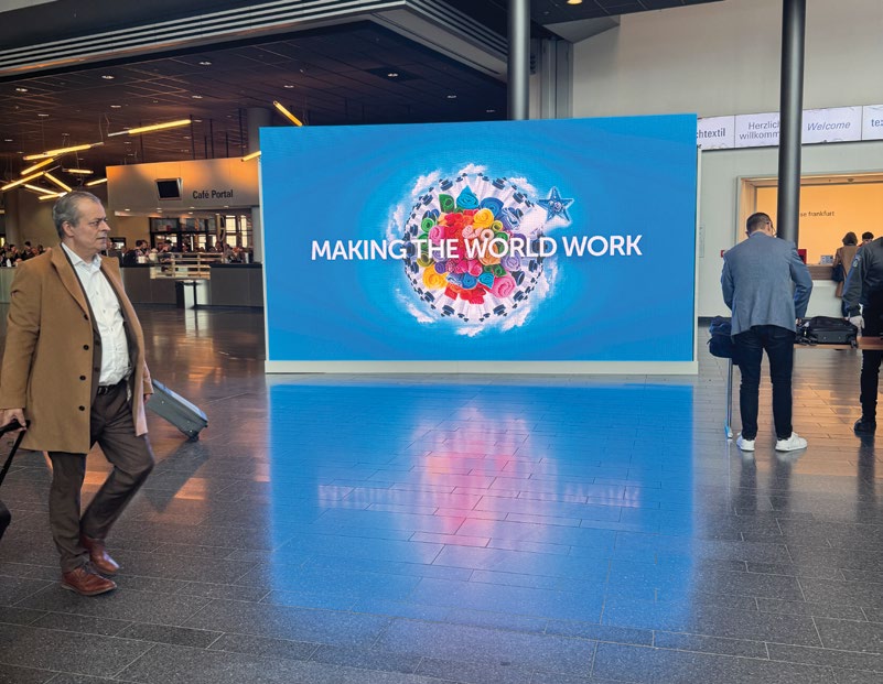 Fuar girişindeki Making The World Work temalı dijital reklam ekranı