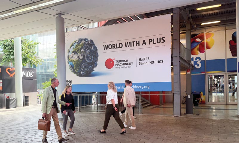 PLAST Milano 2026 fuar girişinde Turkish Machinery 'World With A Plus' reklam panosu, Hall 13