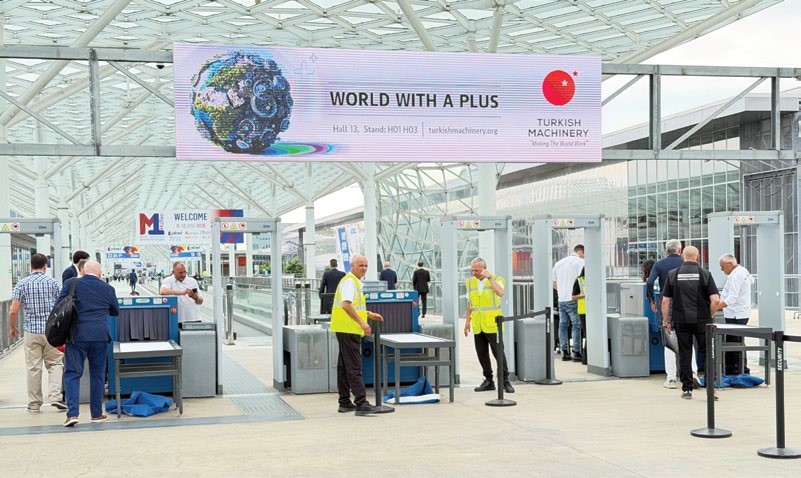 PLAST Milano 2026 fuar girişindeki güvenlik noktası ve Turkish Machinery 'World With A Plus' bannerı