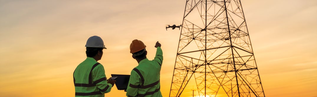 Endüstriyel denetim dronu ile enerji nakil hattı direğini inceleyen saha çalışanları