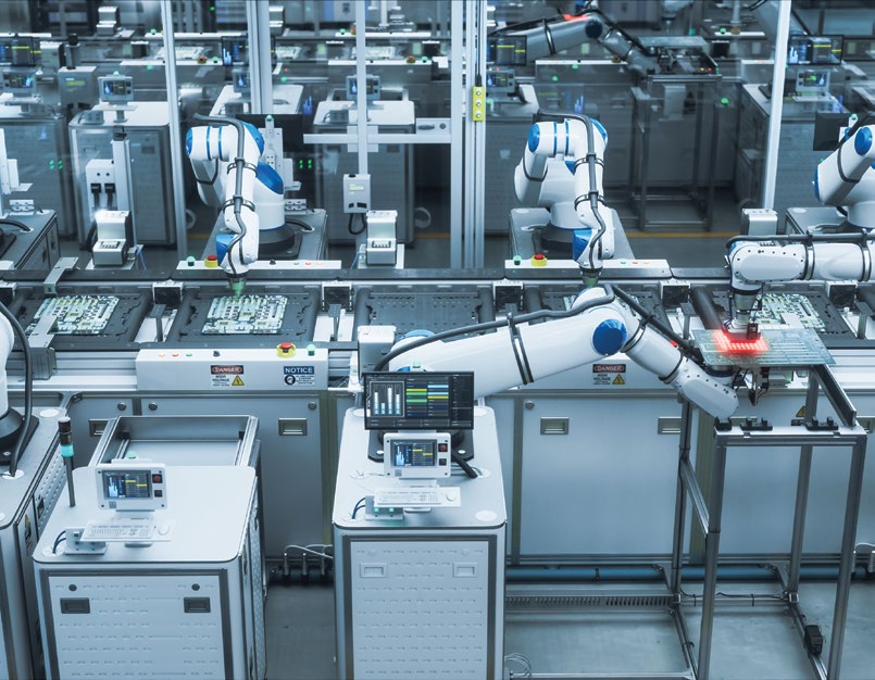 Endüstriyel fabrika ortamında iş birliği yaparak çalışan robotik kollar ve otomasyon istasyonları
