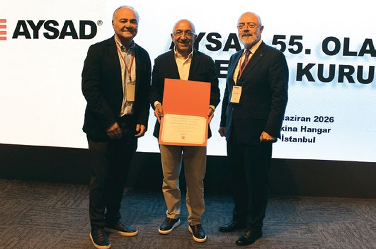AYSAD 55'inci Olağan Genel Kurulunda plaket takdimi; arkada 'AYSAD 55. Olağan Genel Kurul, 10 Haziran 2026, Makina Hangar, İstanbul' pankartı