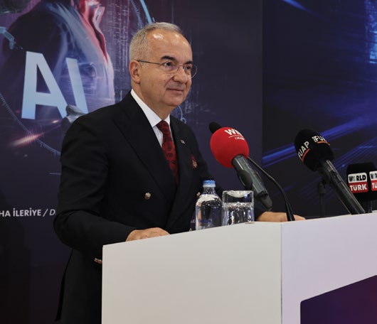 Kutlu Karavelioğlu bir sektör etkinliğinde kürsüde konuşurken, arkasında yapay zekâ temalı fon
