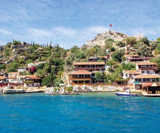 Antalya Kale Üçağız Köyü'nde denize sıfır taş evler, tepedeki Orta Çağ kalesi ve masmavi Kekova sularındaki tekne
